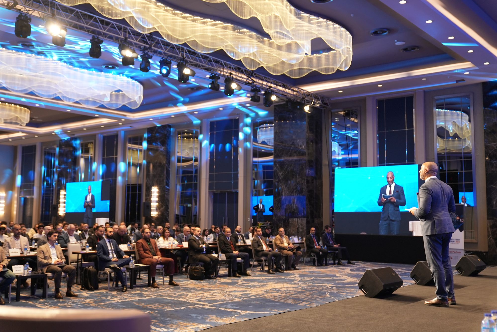Speaker on stage addressing a full conference hall